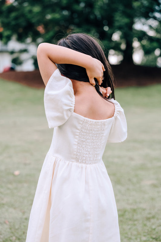 Back view of child wearing SAND Mini Mira Dress in soft sand linen blend