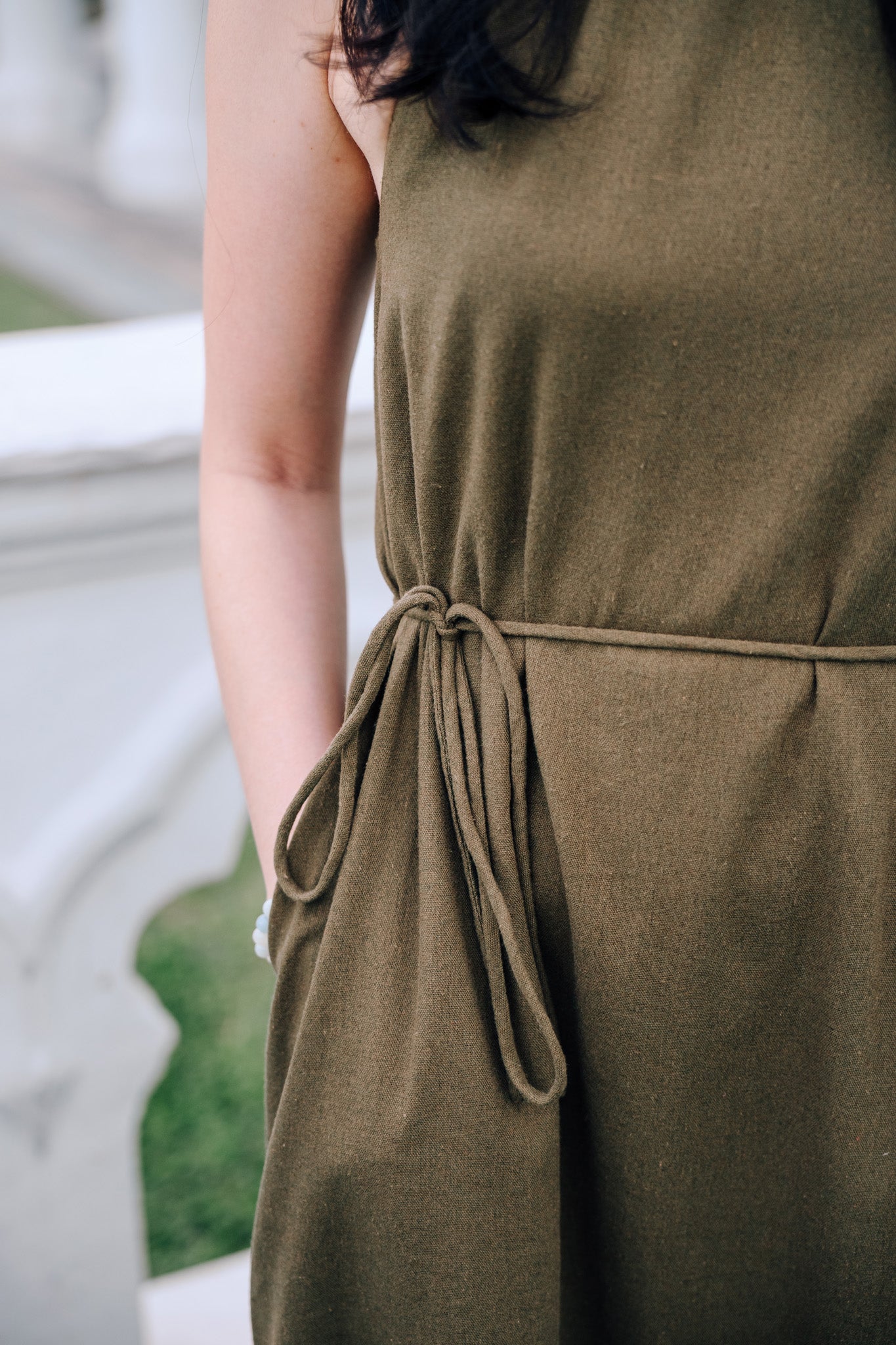 Close up of waist strap of woman wearing MOSS Isla Dress in breathable moss green linen blend