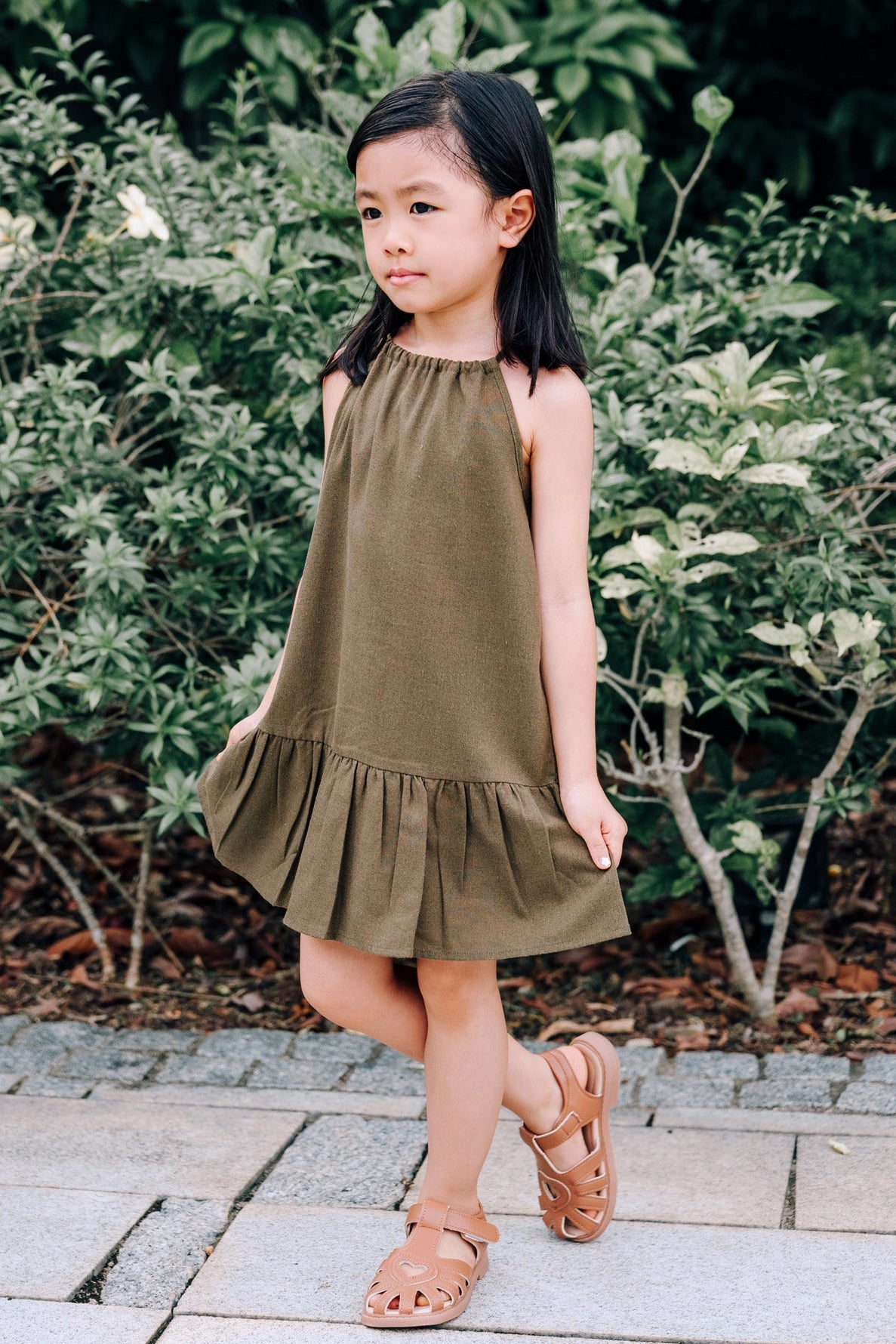 Young girl wearing MOSS Mini Isla Dress in soft moss green linen fabric