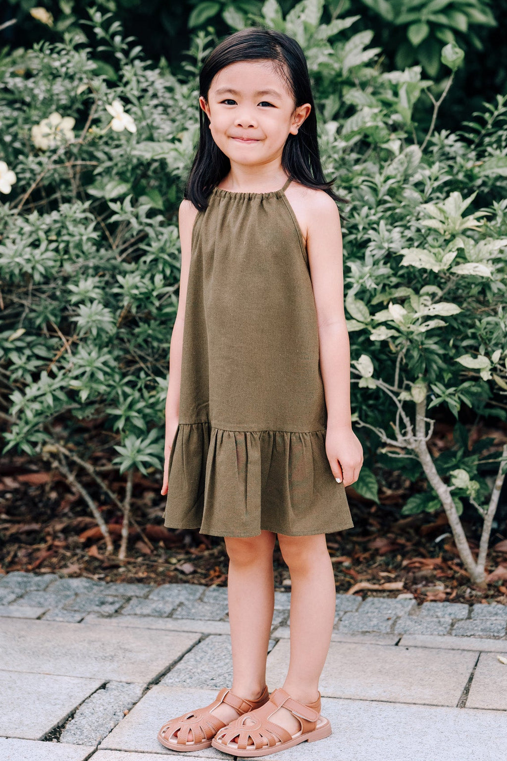 Young girl wearing MOSS Mini Isla Dress in soft moss green linen fabric