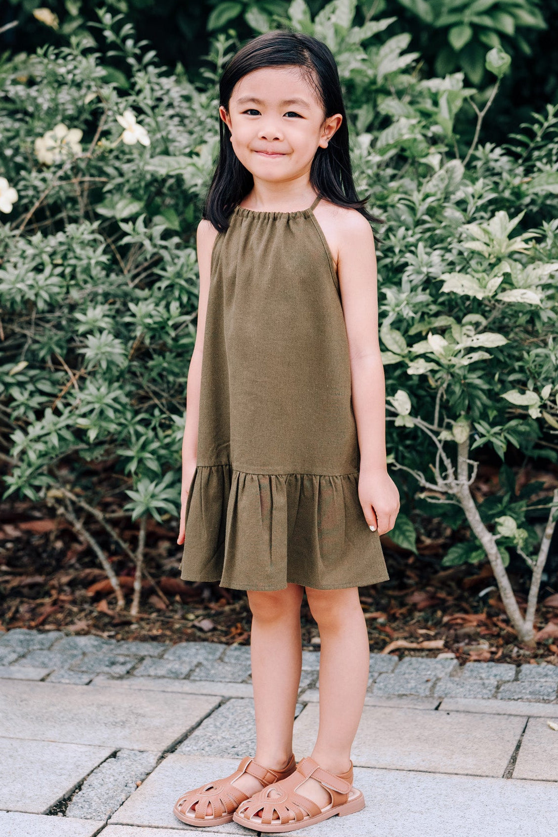 Young girl wearing MOSS Mini Isla Dress in soft moss green linen fabric