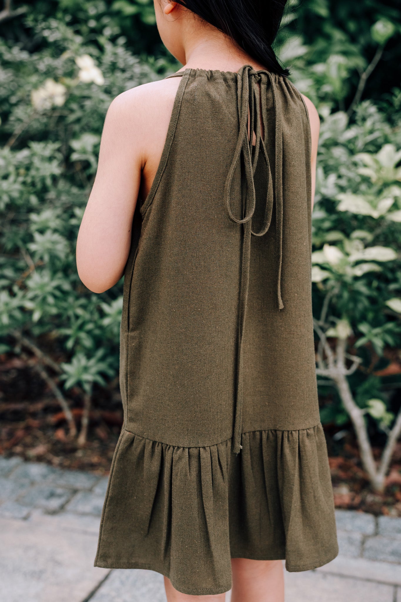 Back of young girl wearing MOSS Mini Isla Dress in soft moss green linen blend fabric