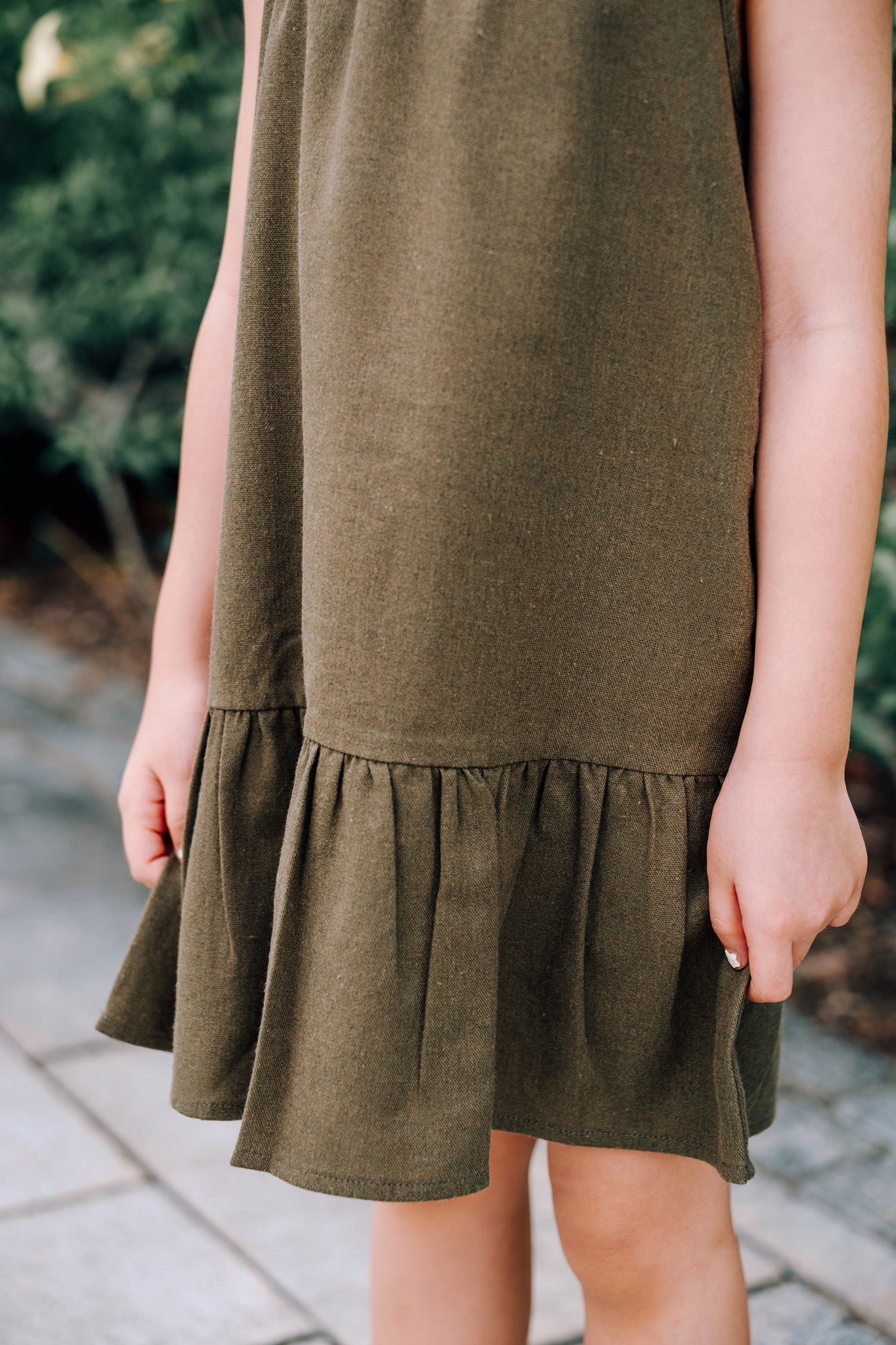 Close up of young girl wearing MOSS Mini Isla Dress in soft moss green linen blend fabric