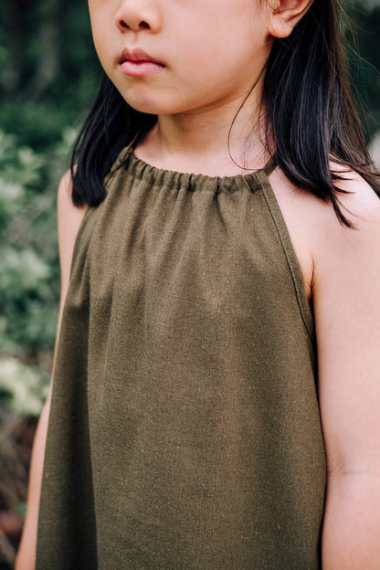 Close up of young girl wearing MOSS Mini Isla Dress in soft moss green linen blend fabric