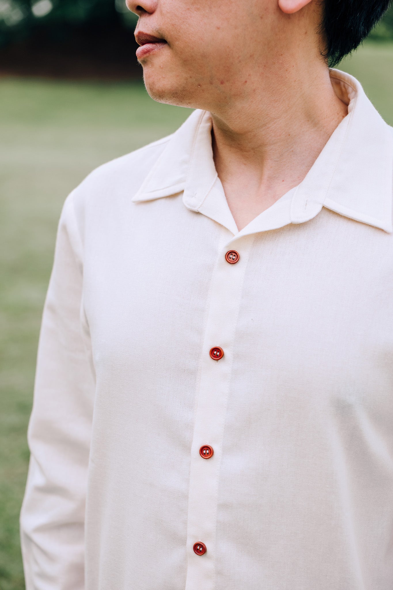 Close up of collar and faux wooden buttons of man wearing SAND Elio Shirt in breathable sand linen blend