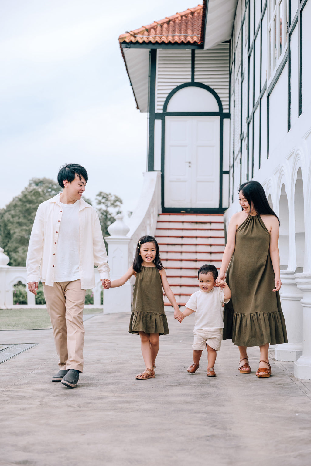 Family wearing coordinated SAND and MOSS Collection outfits featuring Elio Shirt, Mini Noa T-Shirt, Isla Dress and Mini Isla Dress