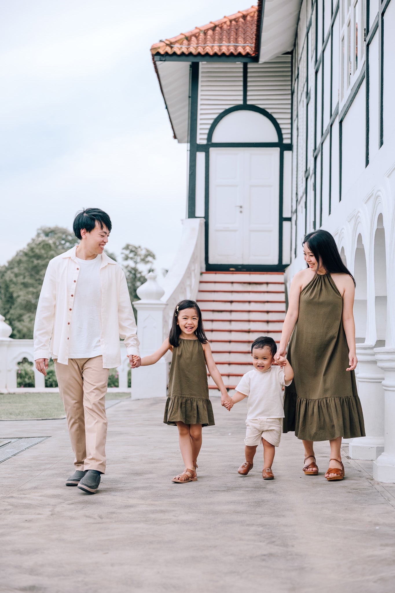 Family wearing coordinated SAND and MOSS Collection outfits featuring Elio Shirt, Mini Noa T-Shirt, Isla Dress and Mini Isla Dress