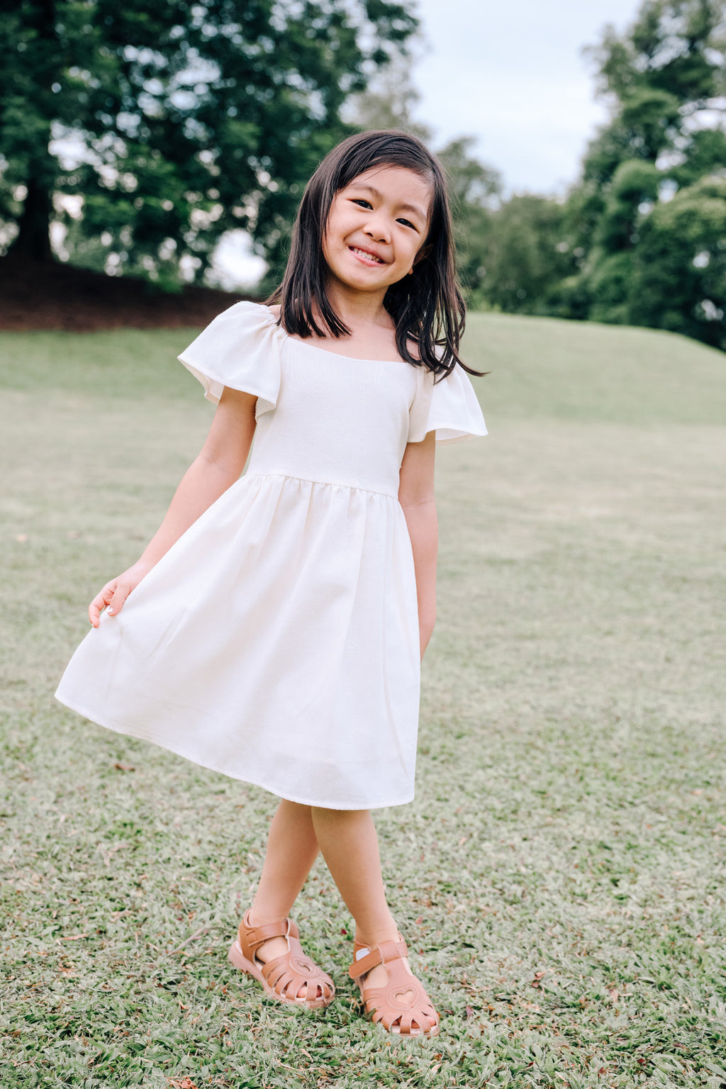 Child wearing SAND Mini Mira Dress in soft sand linen blend
