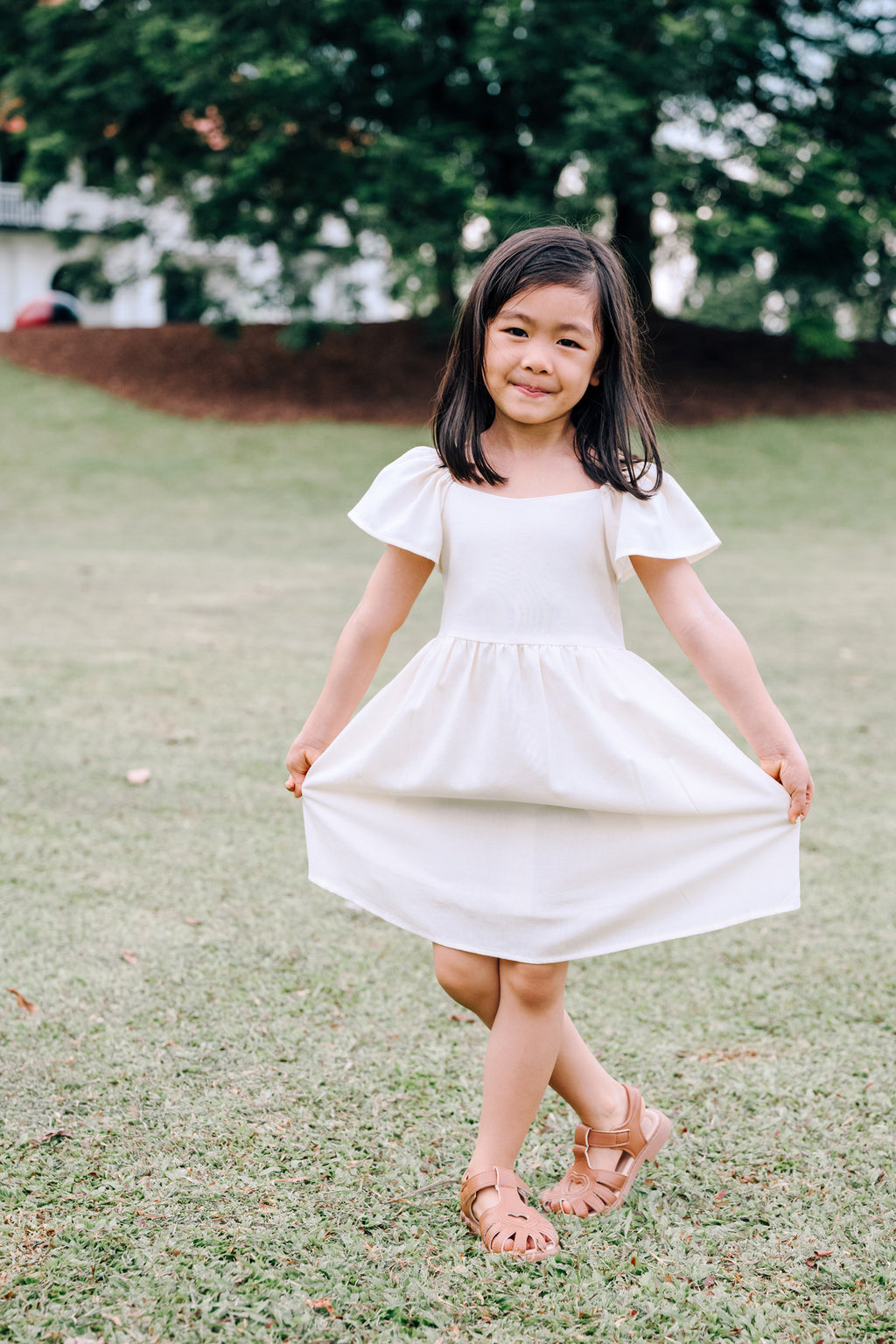 Child wearing SAND Mini Mira Dress in soft sand linen blend