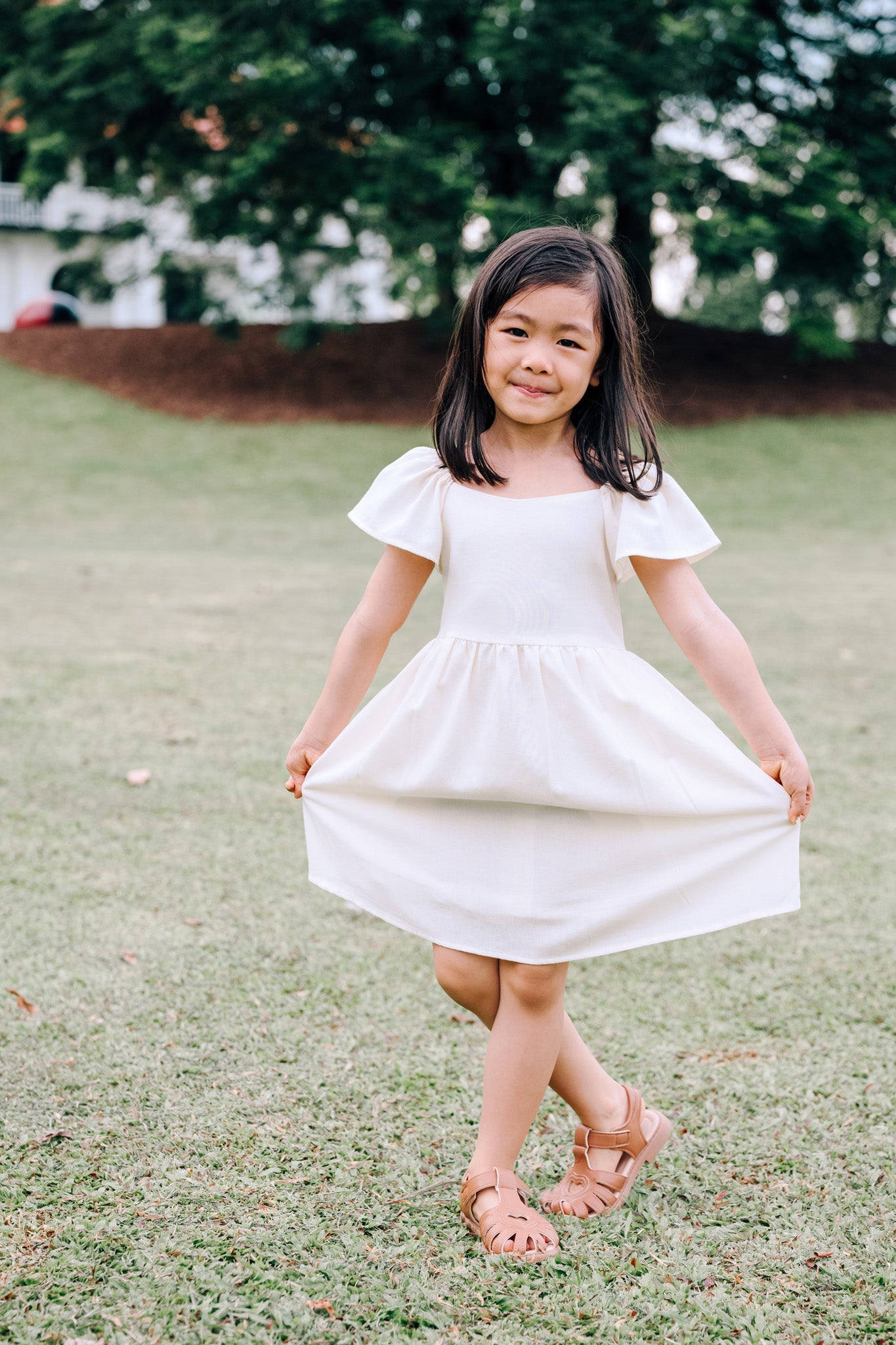 Child wearing SAND Mini Mira Dress in soft sand linen blend
