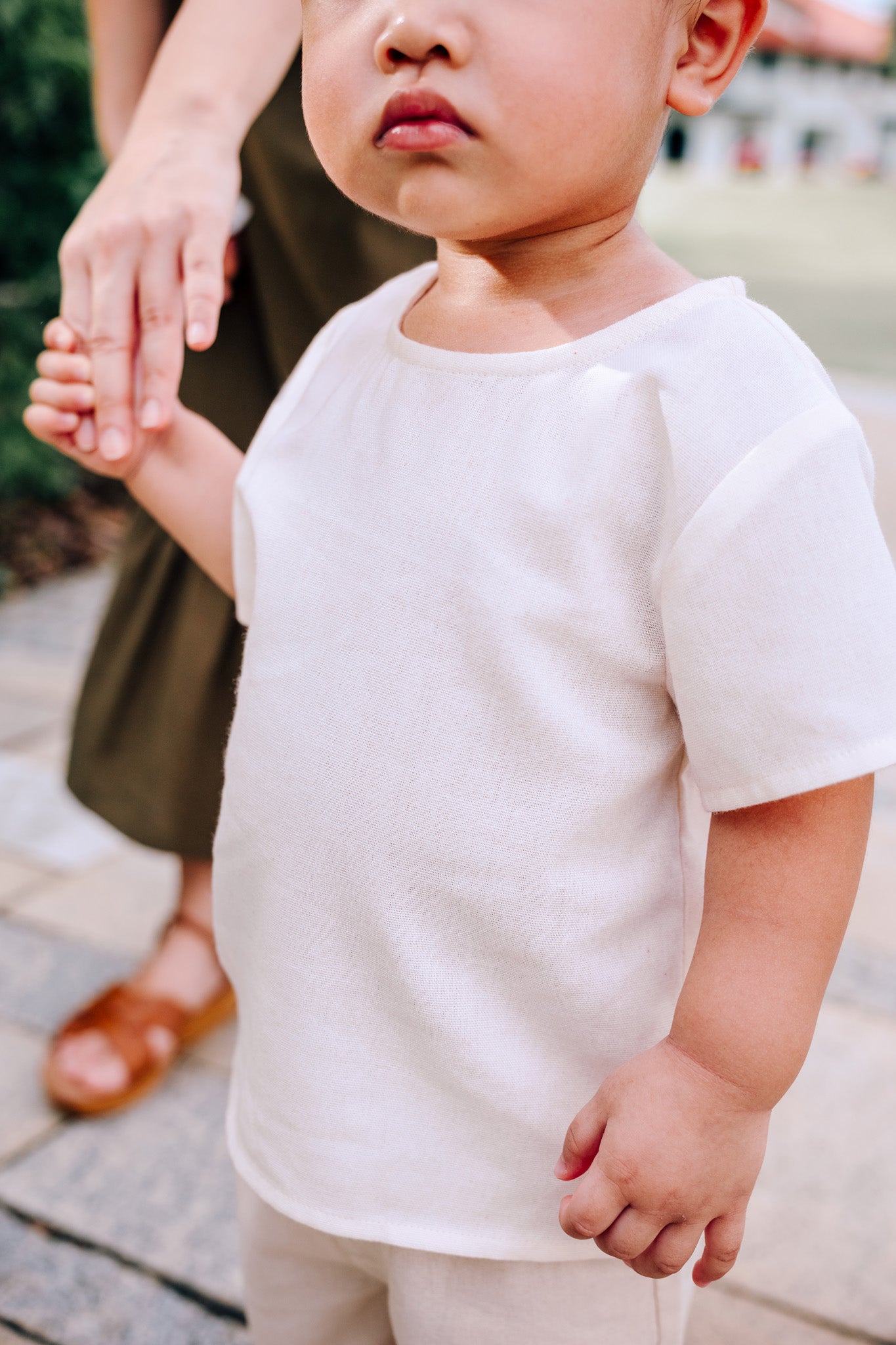 Close up of child wearing SAND Mini Noa T-Shirt in neutral tone sand linen blend fabric