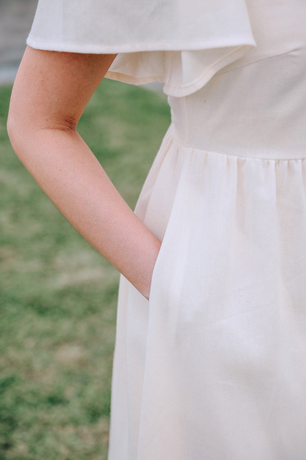 Close-up of side pocket of SAND Mira A-Line Dress smocked back and ruffle sleeves in sand