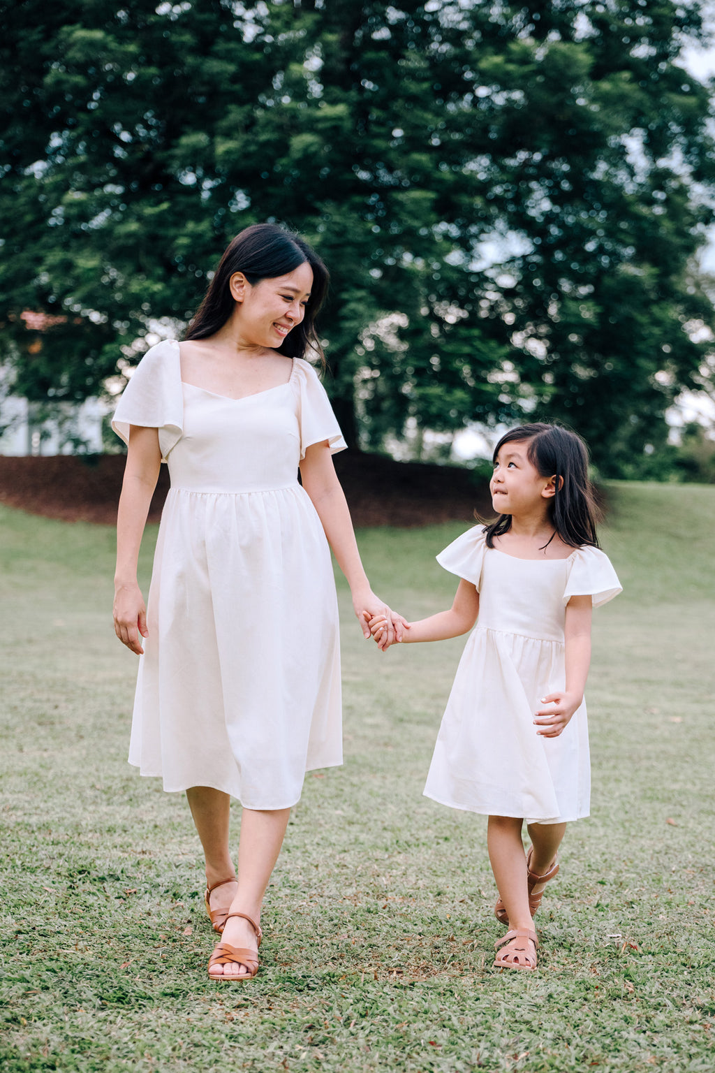 Mother and daughter wearing SAND Mira and SAND Mini Mira matching linen dresses in sand