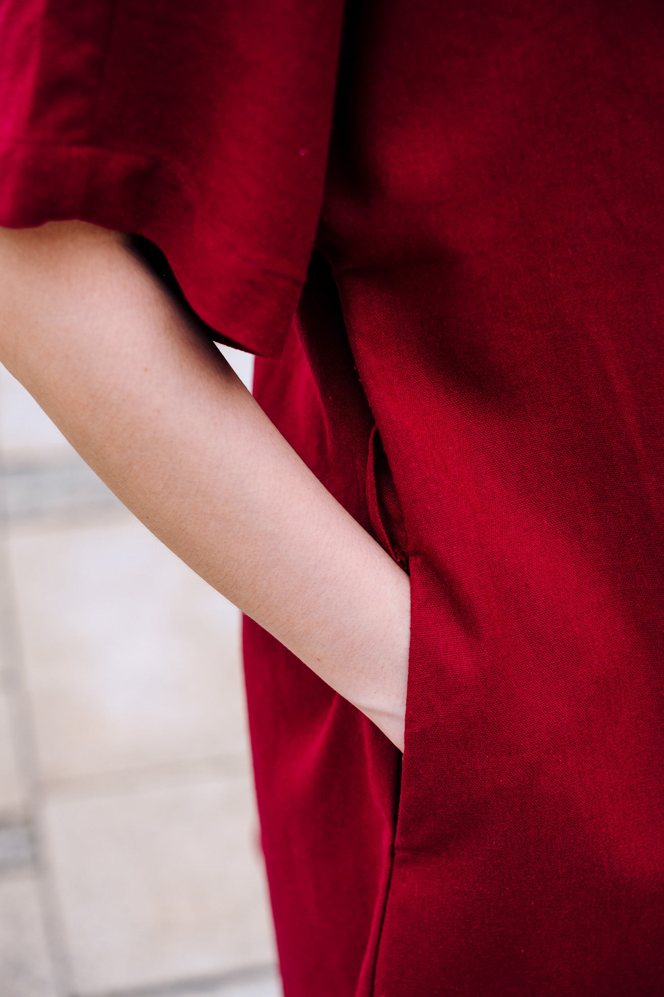 Close-up of hands inside burgundy linen dress pocket