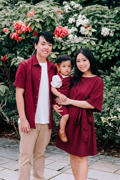 A family of three wearing matching burgundy linen shirt, dungaree and dress.